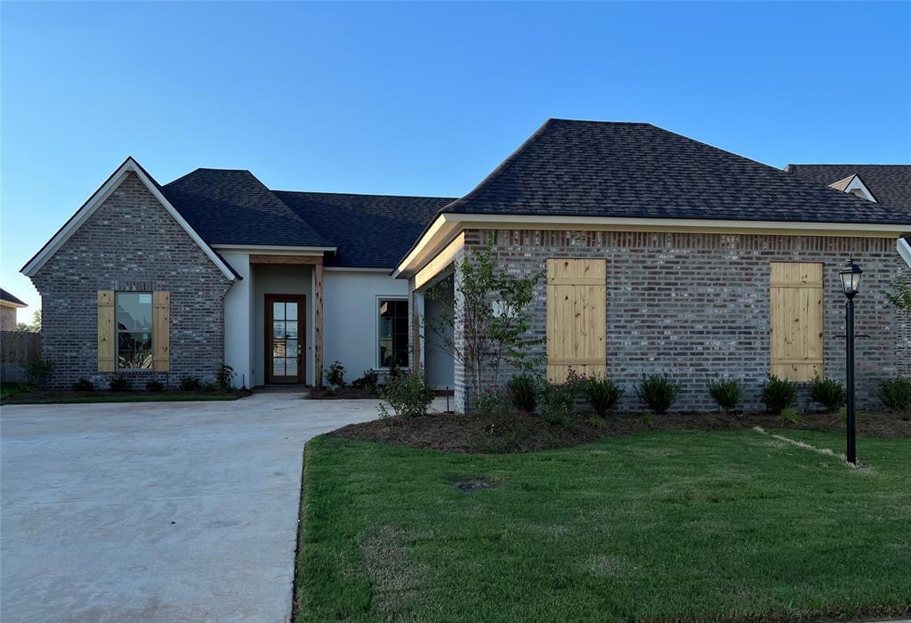 A large new construction home with gray brick siding and natural wood trim
